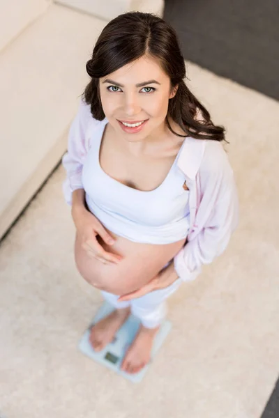 Pregnant woman standing on scales — Stock Photo
