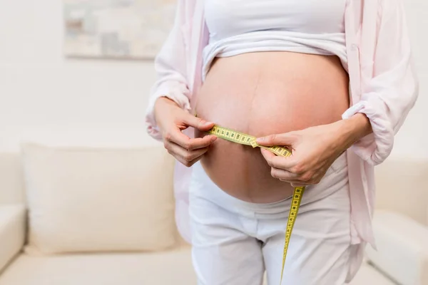 Pregnant woman with flexible ruler — Stock Photo