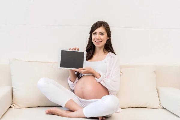 Беременная женщина показывает цифровой планшет — стоковое фото