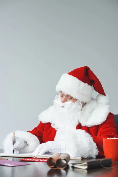 Санта-Клаус пишет за столом — стоковое фото