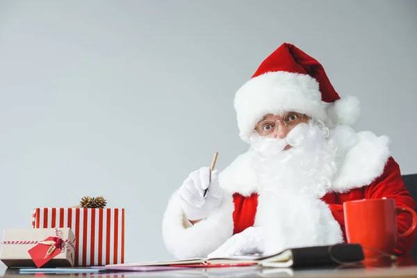 Weihnachtsmann schreibt am Tisch — Stockfoto