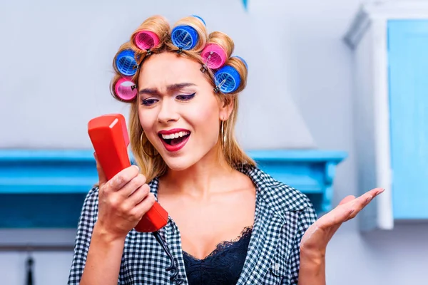 Angry housewife talking on telephone — Stock Photo