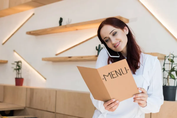 Woman talking by phone and looking at menu — Stock Photo