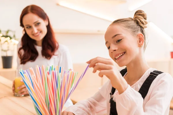 Teen girl choosing straw in cafe — Stock Photo