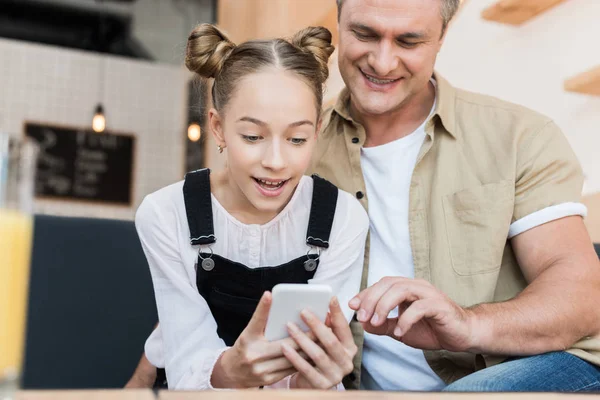 Vater und Tochter schauen aufs Smartphone — Stockfoto