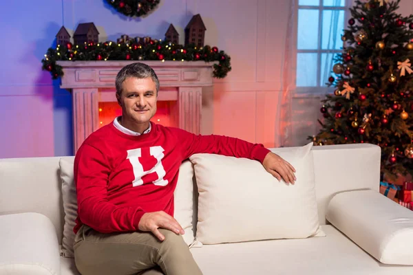 Зрілий чоловік сидить на дивані на Різдво — стокове фото
