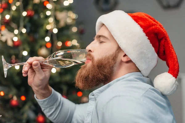 Людина в капелюсі Санта п'є шампанське — стокове фото