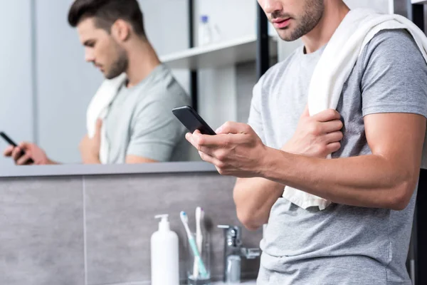 Homme utilisant smartphone dans la salle de bain — Photo de stock