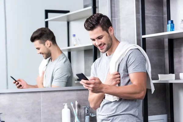 Homme utilisant smartphone dans la salle de bain — Photo de stock