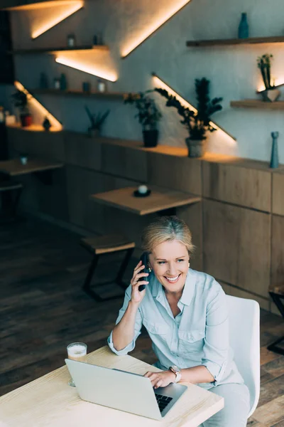 Businesswoman talking on smartphone in cafe — Stock Photo