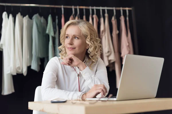 Businesswoman with laptop in clothing store — Stock Photo