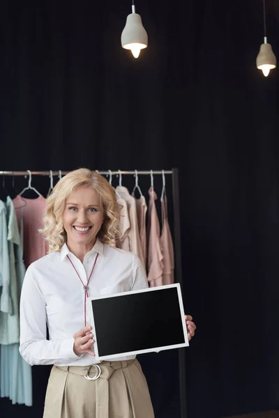 Frau mit leerer Tafel in Bekleidungsgeschäft — Stockfoto