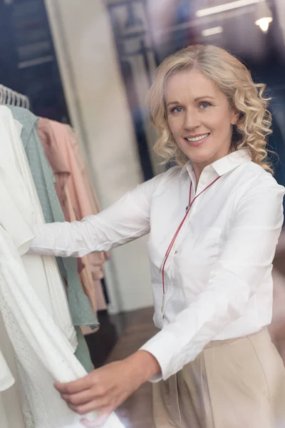 Donna che sceglie i vestiti nel negozio di abbigliamento — Foto stock