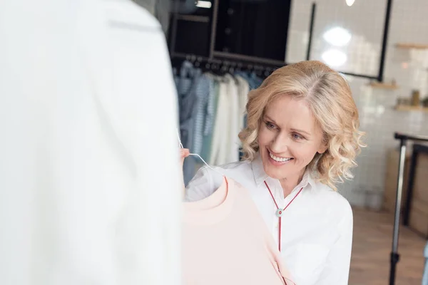 Donna che sceglie i vestiti nel negozio di abbigliamento — Foto stock