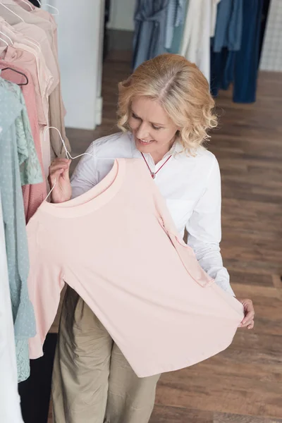 Woman choosing clothes in clothing store — Stock Photo