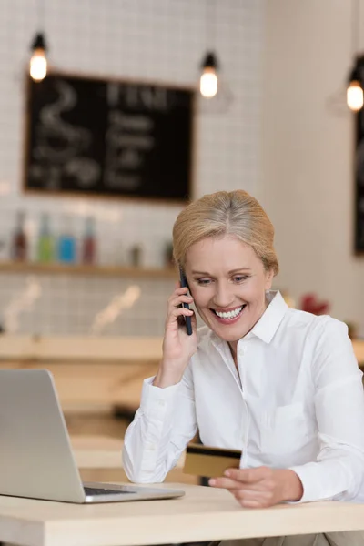 Femme d'affaires avec carte de crédit parlant sur smartphone — Photo de stock