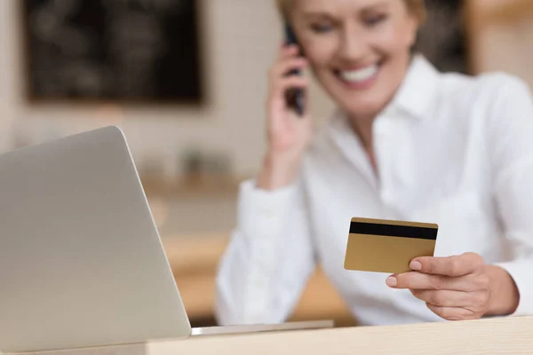 Mujer de negocios con tarjeta de crédito hablando en smartphone - foto de stock