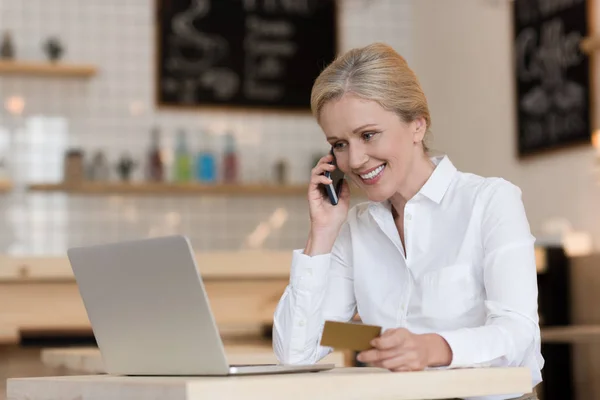 Femme d'affaires avec carte de crédit parlant sur smartphone — Photo de stock