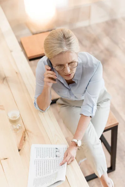 Femme avec smartphone et journal — Photo de stock