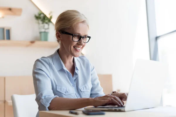 Mulher madura usando laptop — Fotografia de Stock