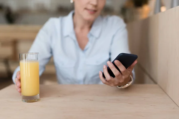 Женщина со смартфоном пьет сок — стоковое фото