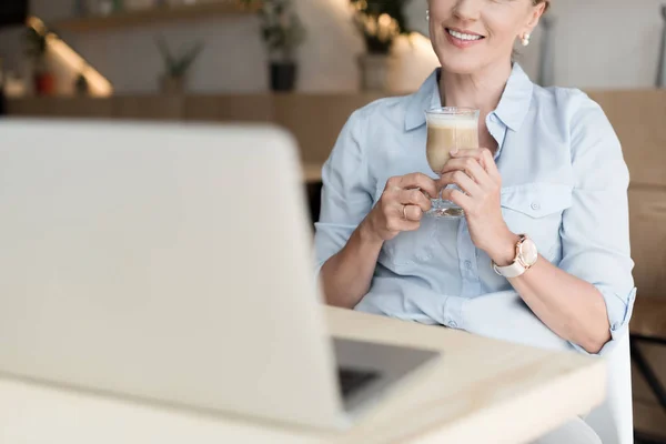 Mulher bebendo café e usando laptop — Fotografia de Stock