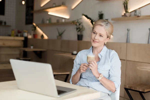 Frau trinkt Kaffee und benutzt Laptop — Stockfoto