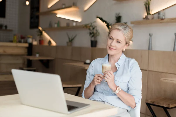 Donna che beve caffè e utilizza computer portatile — Foto stock