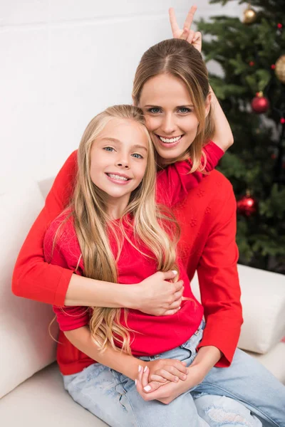 Madre e hija abrazándose en el árbol de Navidad - foto de stock