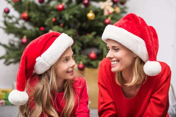 Madre e hija en sombreros de Santa en Navidad - foto de stock