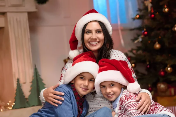 Mère avec des enfants dans chapeaux de Père Noël — Photo de stock