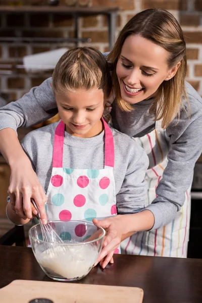 Madre ayudando a hija con la cocina — Stock Photo