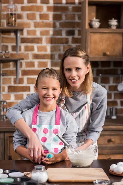 Madre ayudando a hija con la cocina - foto de stock