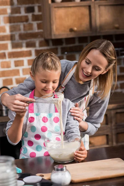 Madre ayudando a hija con la cocina - foto de stock