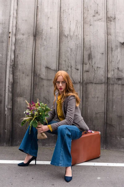 Fille assise sur une valise vintage — Photo de stock