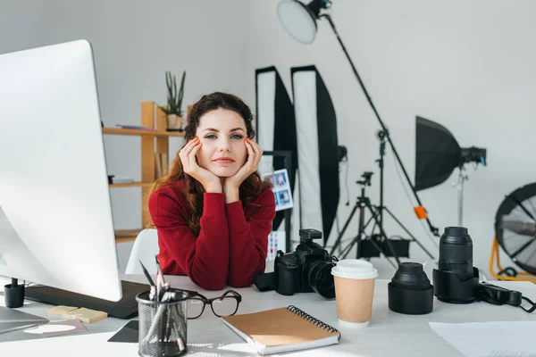 Приваблива жінка-фотограф з лінзами, фотоапаратом і графічним планшетом в сучасному офісі — стокове фото