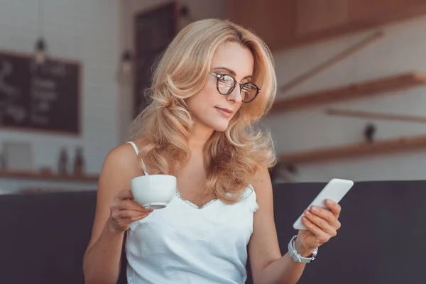 Mujer con café y smartphone - foto de stock