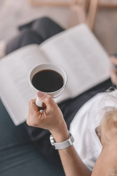 Donna che legge libro e beve caffè — Foto stock