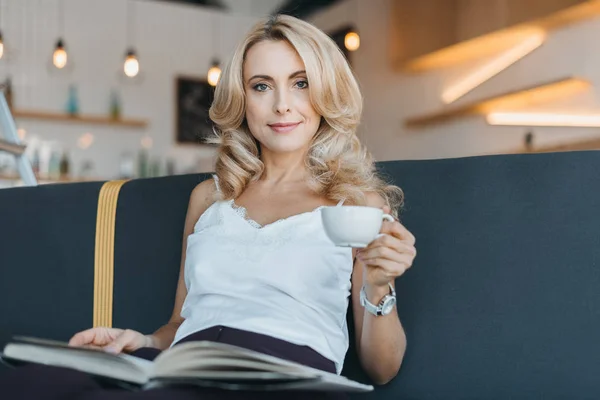 Mujer leyendo libro en la cafetería - foto de stock