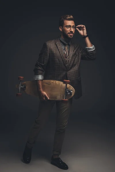 Чоловік у костюмі тримає скейтборд — стокове фото
