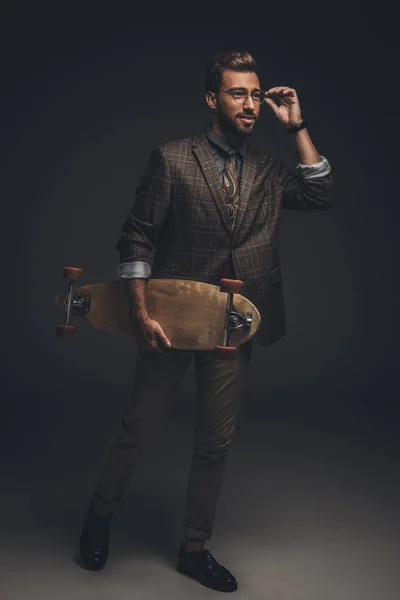 Hombre de traje sosteniendo monopatín - foto de stock