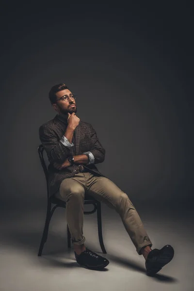 Удумливий чоловік у костюмі сидить на стільці — стокове фото