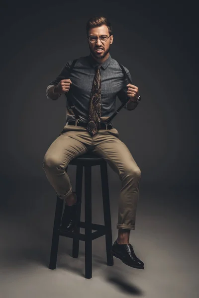 Человек сидит на стуле и тянет подтяжки — стоковое фото
