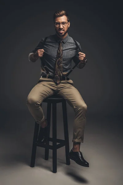 Homme assis sur un tabouret et tirant des bretelles — Photo de stock