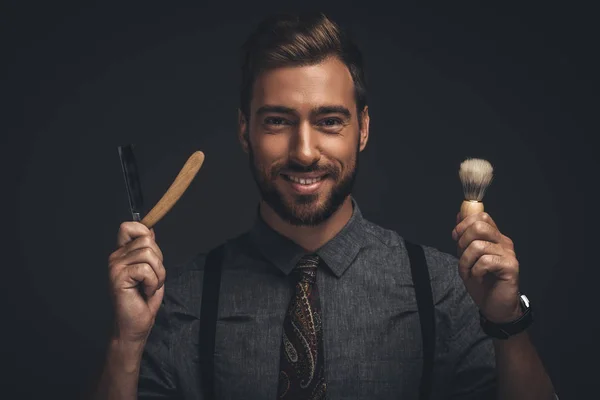 Hombre sosteniendo maquinilla de afeitar y cepillo — Stock Photo