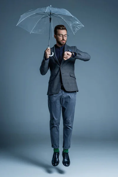 Hombre con paraguas mirando el reloj - foto de stock