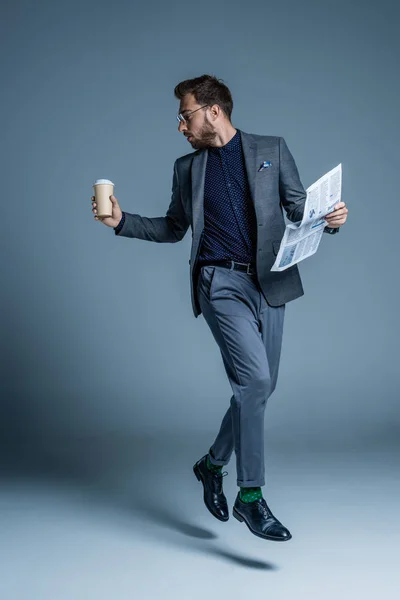 Empresario caminando con café y periódico - foto de stock