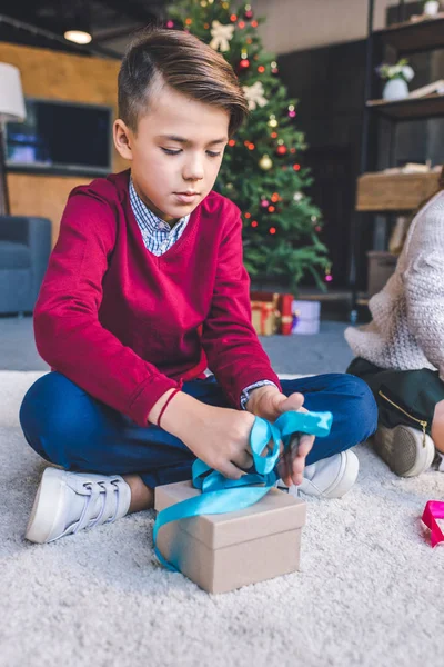 Boy decorating christmas gift — Stock Photo