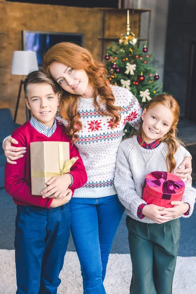 Madre abrazando con niños en Navidad - foto de stock