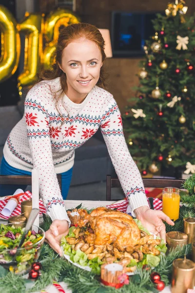 Woman serving christmas table with chicken — Stock Photo